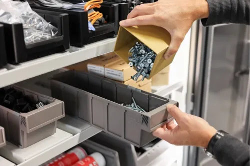 Small parts being refilled from the supplier's box into a bin