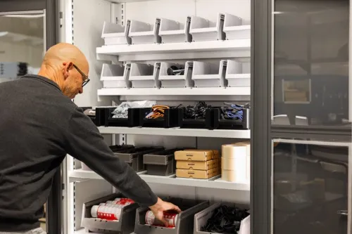An employee refilling items in the cabinet